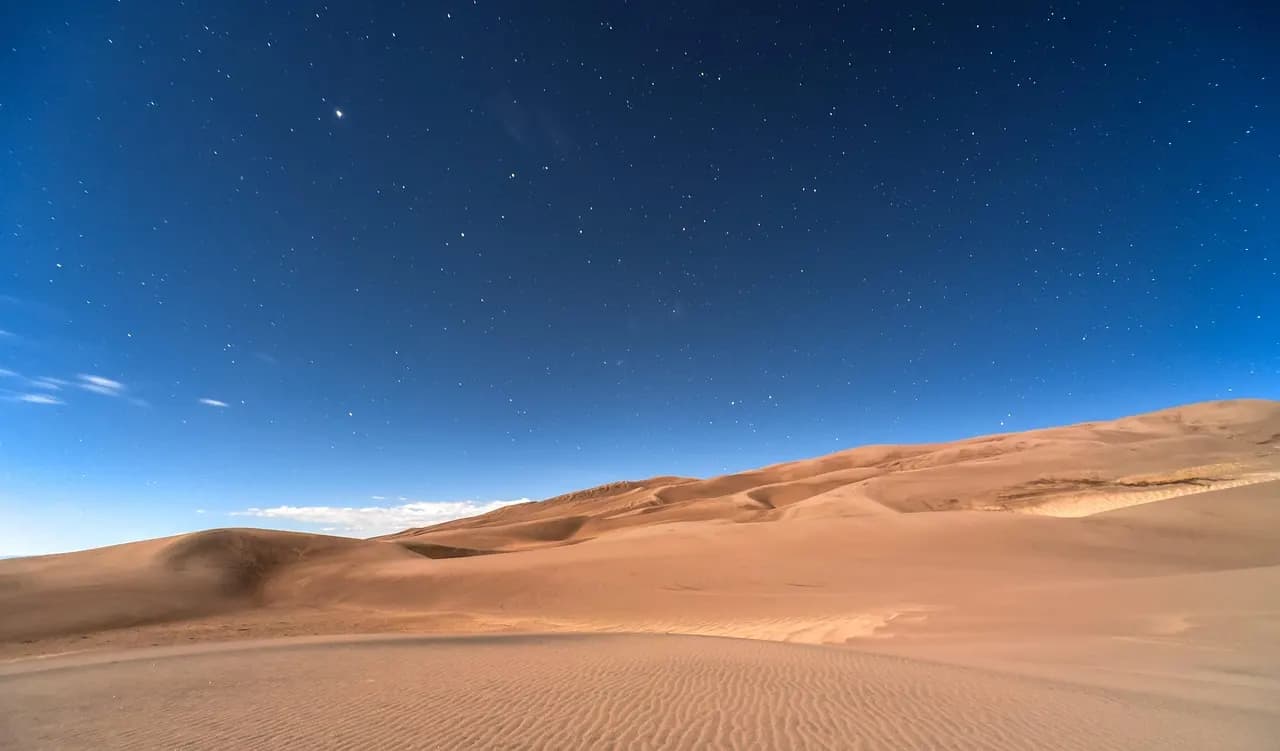 Dunas del desierto al anochecer bajo un cielo azul profundo
