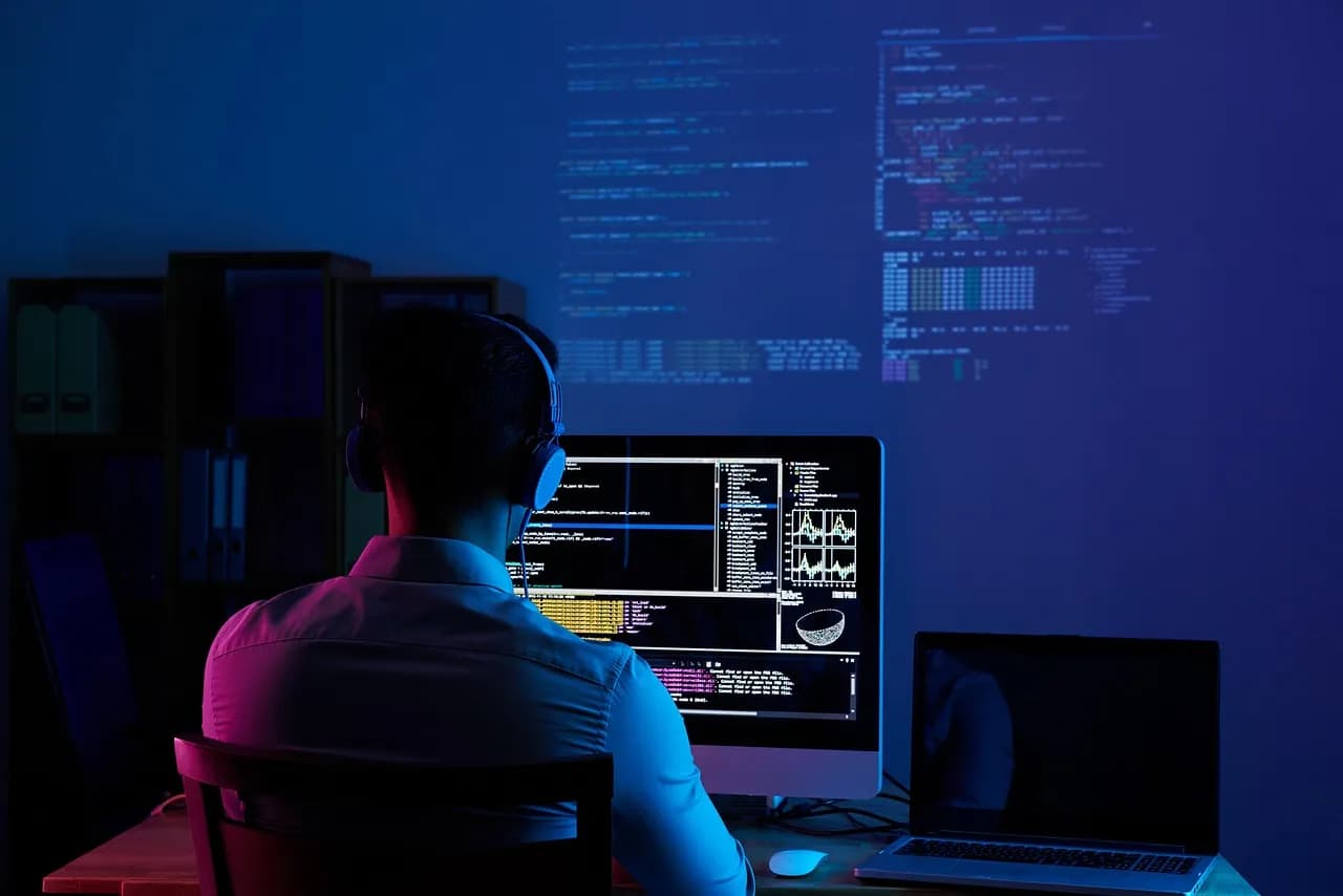 Desarrollador ante su monitor en la oscuridad, construyendo software